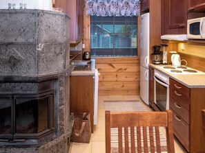 Una cocina con chimenea de piedra, armarios de madera, un microondas y una estufa.