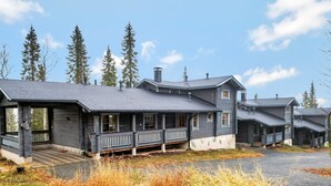 A large, multi-story log cabin with a porch and a covered entryway.