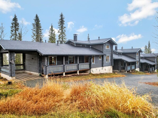 Une grande cabane en rondins à plusieurs étages, dotée d’un porche et d’un hall d’entrée abrité.