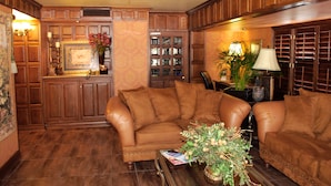 A living room with a brown leather sofa, a coffee table, and a bookshelf. - El Dorado Inn (Delicias)