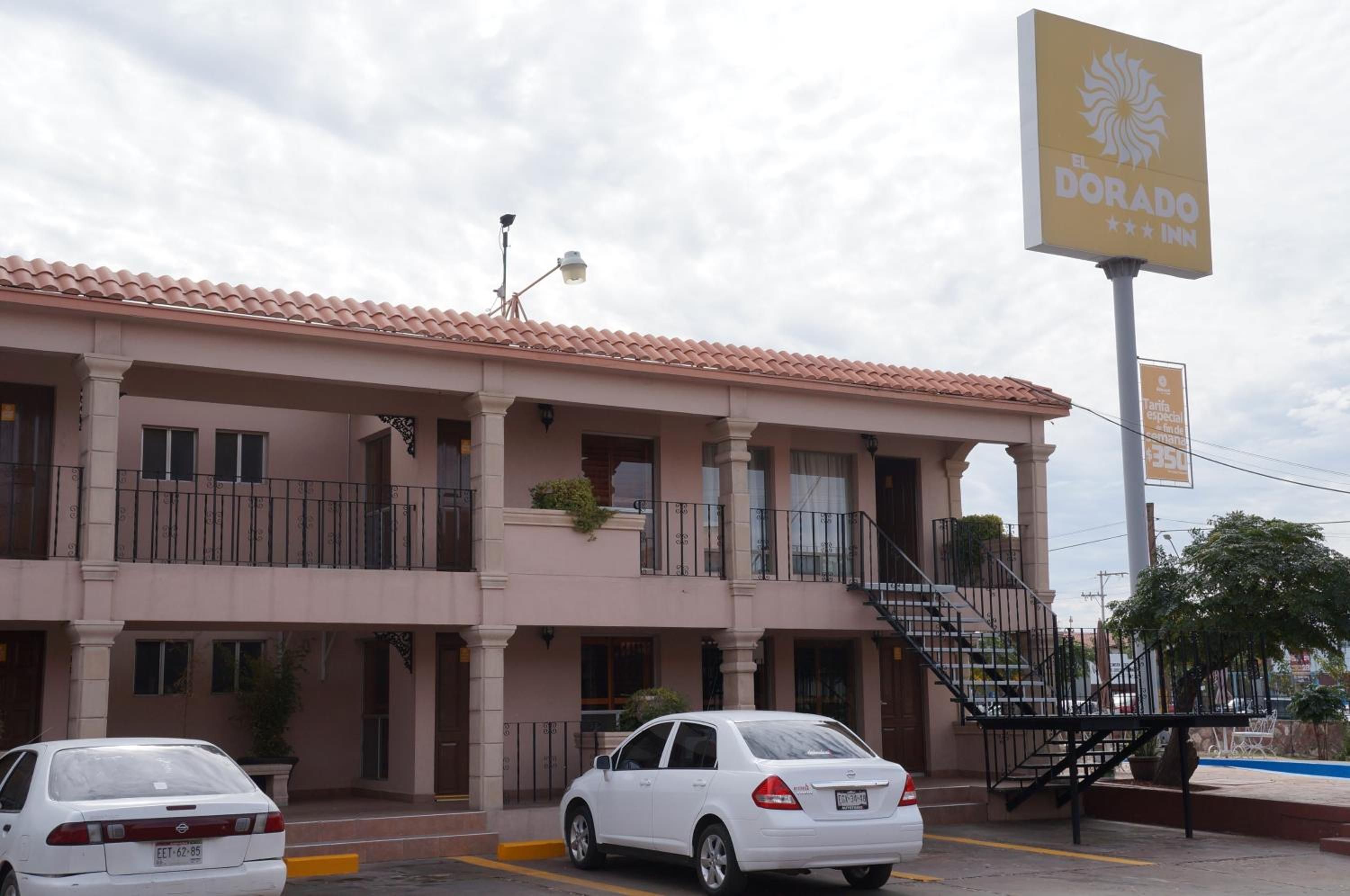 A hotel with a sign for 'El Dorado Inn' and a parking lot with two cars.