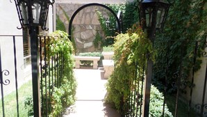 A gated entrance with a stone wall and a bench in the center. - El Dorado Inn (Delicias)
