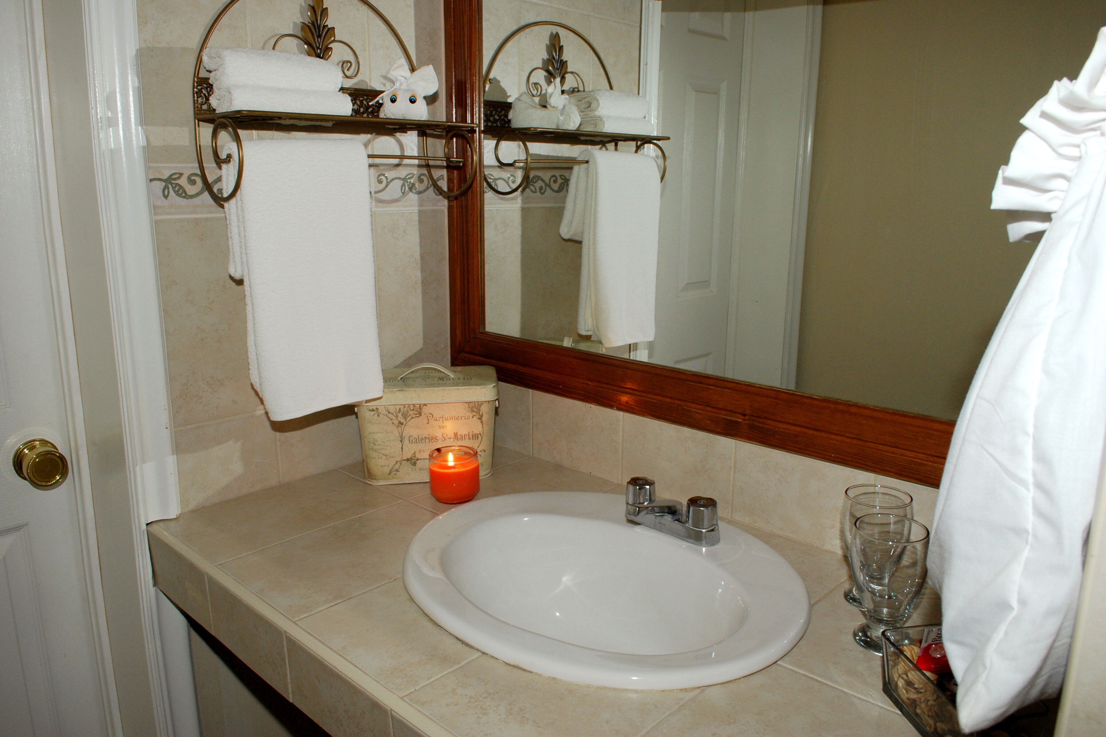 A bathroom with a white sink, a mirror, and a towel rack with folded towels.