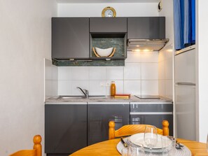 A compact kitchen with a sink, stove, and a clock on the wall.