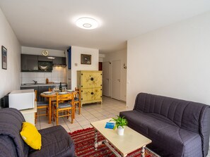 A compact living space with a kitchenette, a dining area, and a seating area with two sofas and a coffee table.