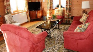 Un salon chaleureux avec un canapé rouge, un téléviseur et un meuble en bois.
