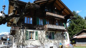 Un chalet traditionnel avec une façade en bois, des volets verts et un balcon.