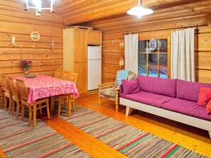 A cozy cabin interior with a dining table, chairs, a sofa, and a refrigerator. - Honkakoti by Interhome (Kuopio)