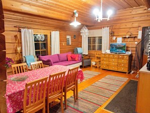 A cozy cabin interior with a dining area, a sofa, a TV, and a wooden dresser. - Honkakoti by Interhome (Kuopio)