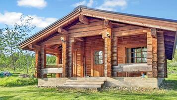 Une cabane en bois avec une véranda, de grandes fenêtres et une cheminée.