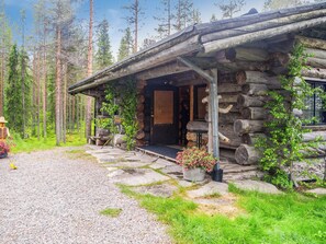A rustic log cabin with a porch, surrounded by a forest. - Puuhamaa by Interhome (Rovaniemi)