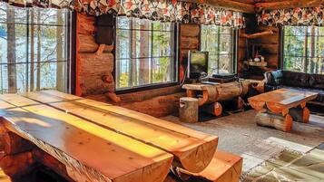 Ein rustikales Blockhaus-Interieur mit einem großen Holztisch, einem Fernseher und einem Sofa.