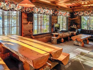 A rustic cabin interior with a large wooden table, a television, and a sofa. - Puuhamaa by Interhome (Rovaniemi)