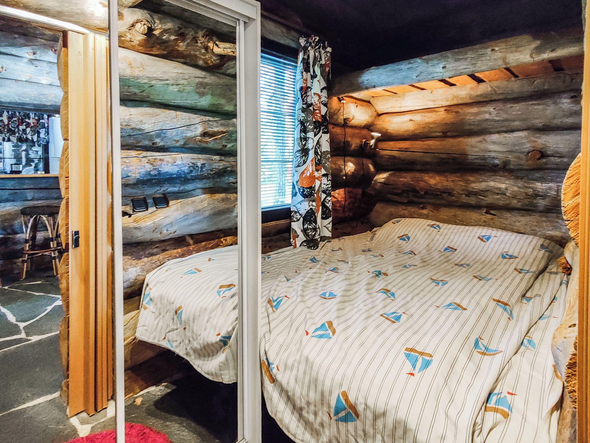 Une chambre de style rustique, avec un lit, une fenêtre équipée de stores et une porte en bois.