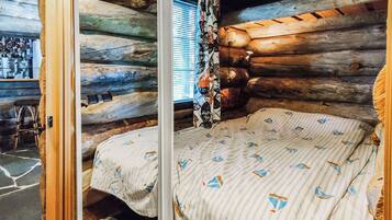 Une chambre de style rustique, avec un lit, une fenêtre équipée de stores et une porte en bois.