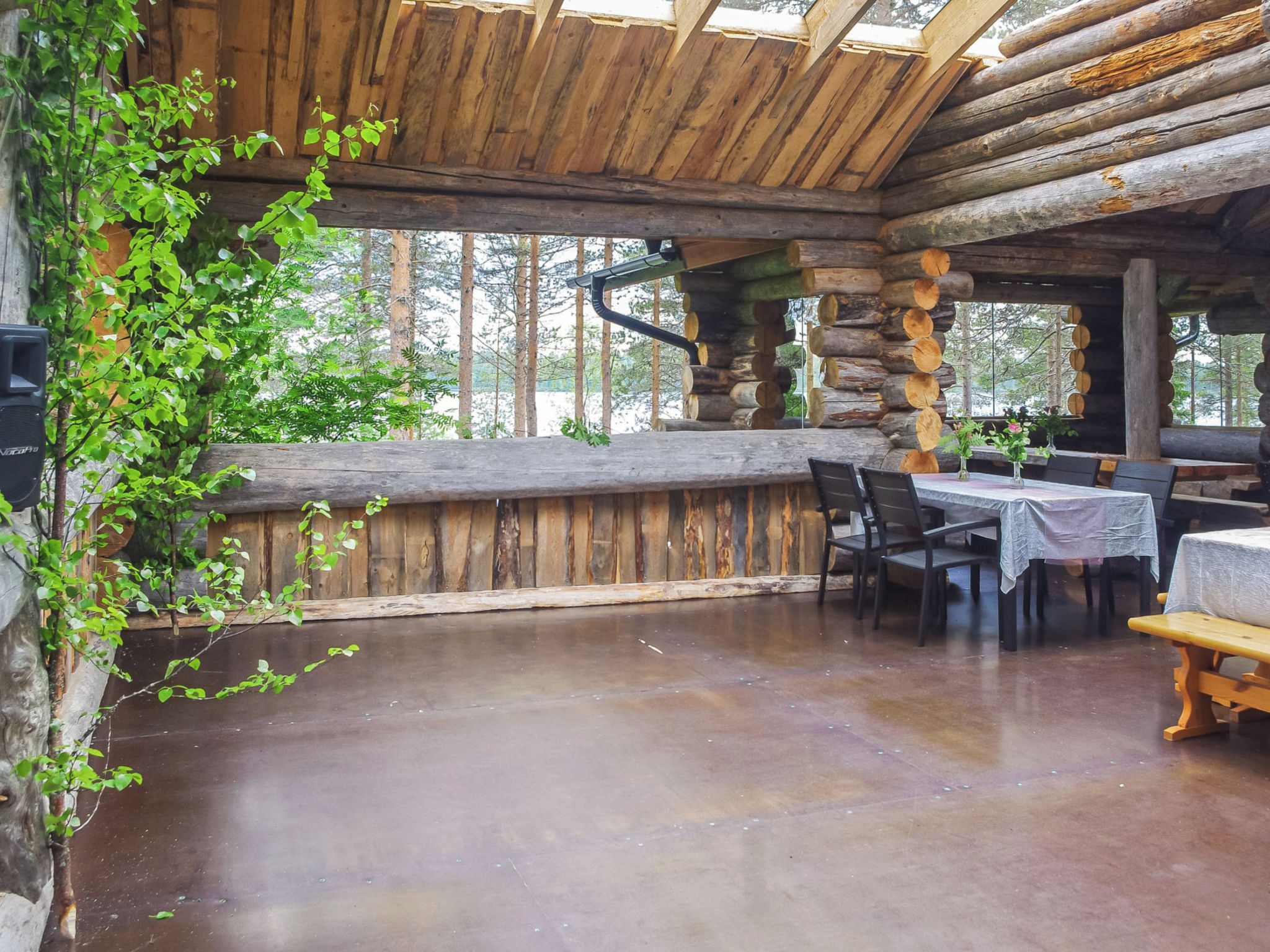 A rustic wooden interior with a stone wall, wooden ceiling beams, and a dining area with tables and chairs.