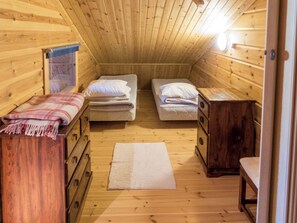 Eine kleine Holzhütte mit zwei Betten, einem Holzschrank und einer Bank.
