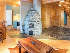 Ein rustikales Interieur mit Kamin aus Stein, Holzmöbeln und einer Küchenzeile.