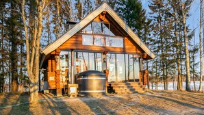 A cabin with a large glass window, a wooden exterior, and a metal water tank. - Huvilakoti 1 by Interhome (Liperi)