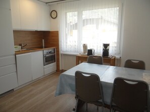 A compact kitchen with a sink, stove, and a clock on the wall.