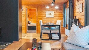 Interior acogedor de una cabaña de madera con comedor, sofá y cama.