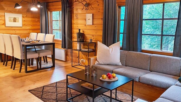 Interior acogedor de una cabaña con comedor, sofá y una mesa llena de fruta.