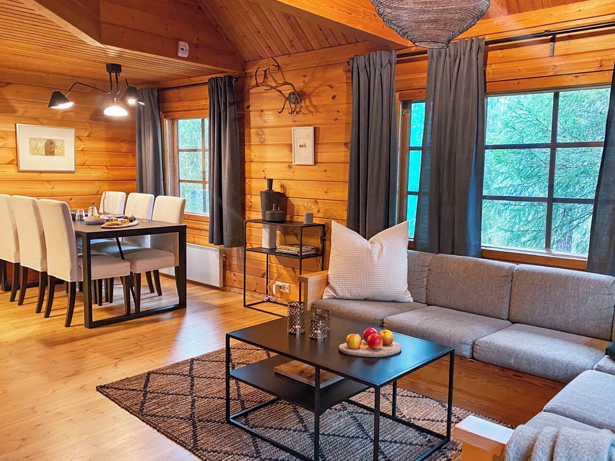 A cozy cabin interior with a dining area, a sofa, and a coffee table.