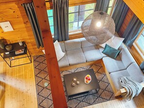 A modern living room with a sectional sofa, a coffee table, and a hanging light fixture.