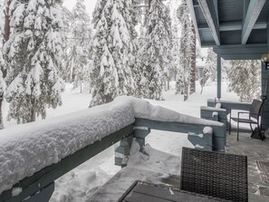A snow-covered deck with a wooden railing, a bench, and a chair. - Uolevintie 39b by Interhome (Kuusamo)