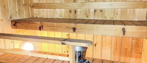 A wooden interior with a metal bucket and a wooden spoon on a shelf.