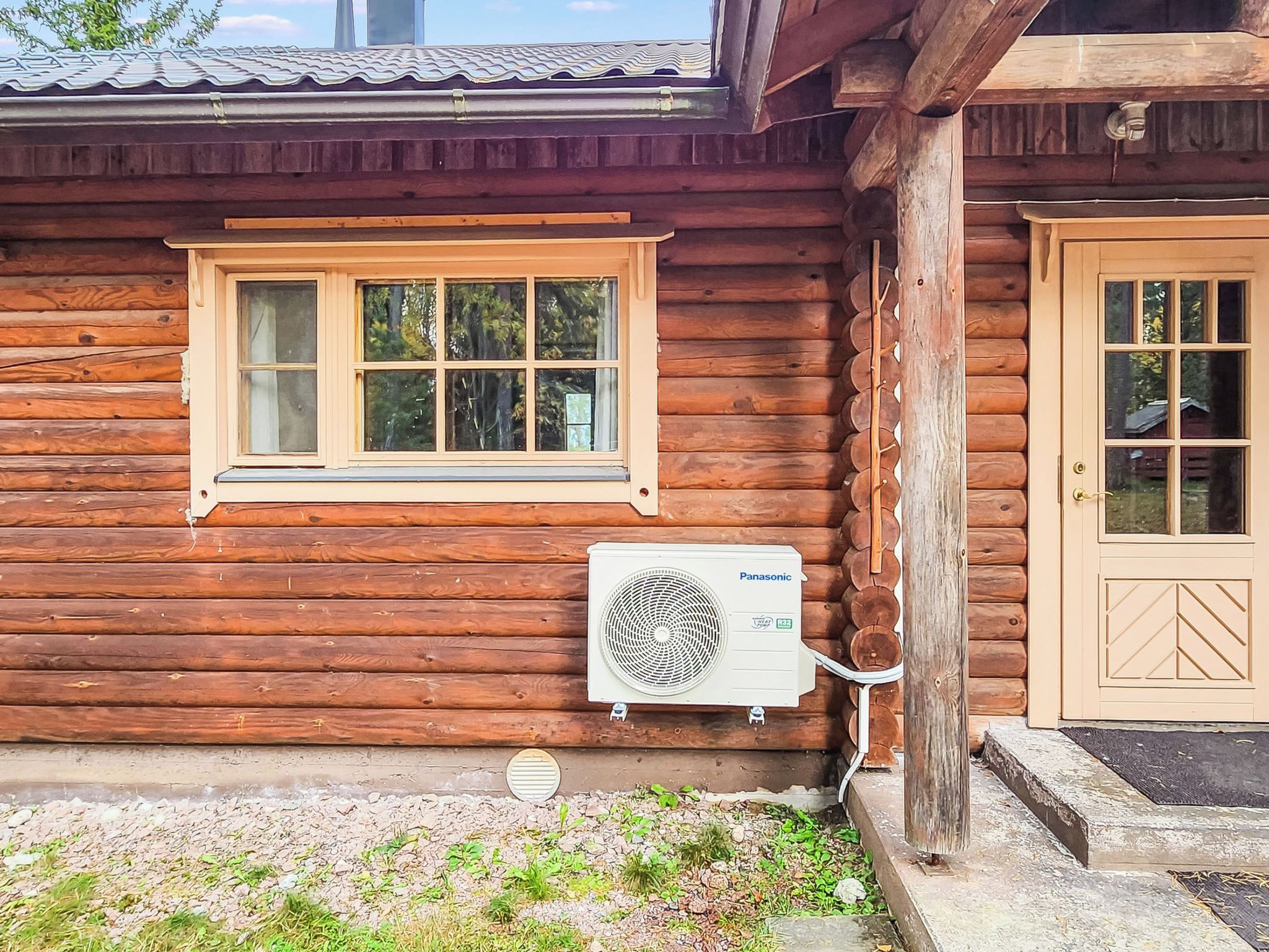 Eine Holzhütte mit Fenster, Klimaanlage und Tür.