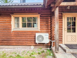 Een houten hut met een raam, een airconditioning en een deur.