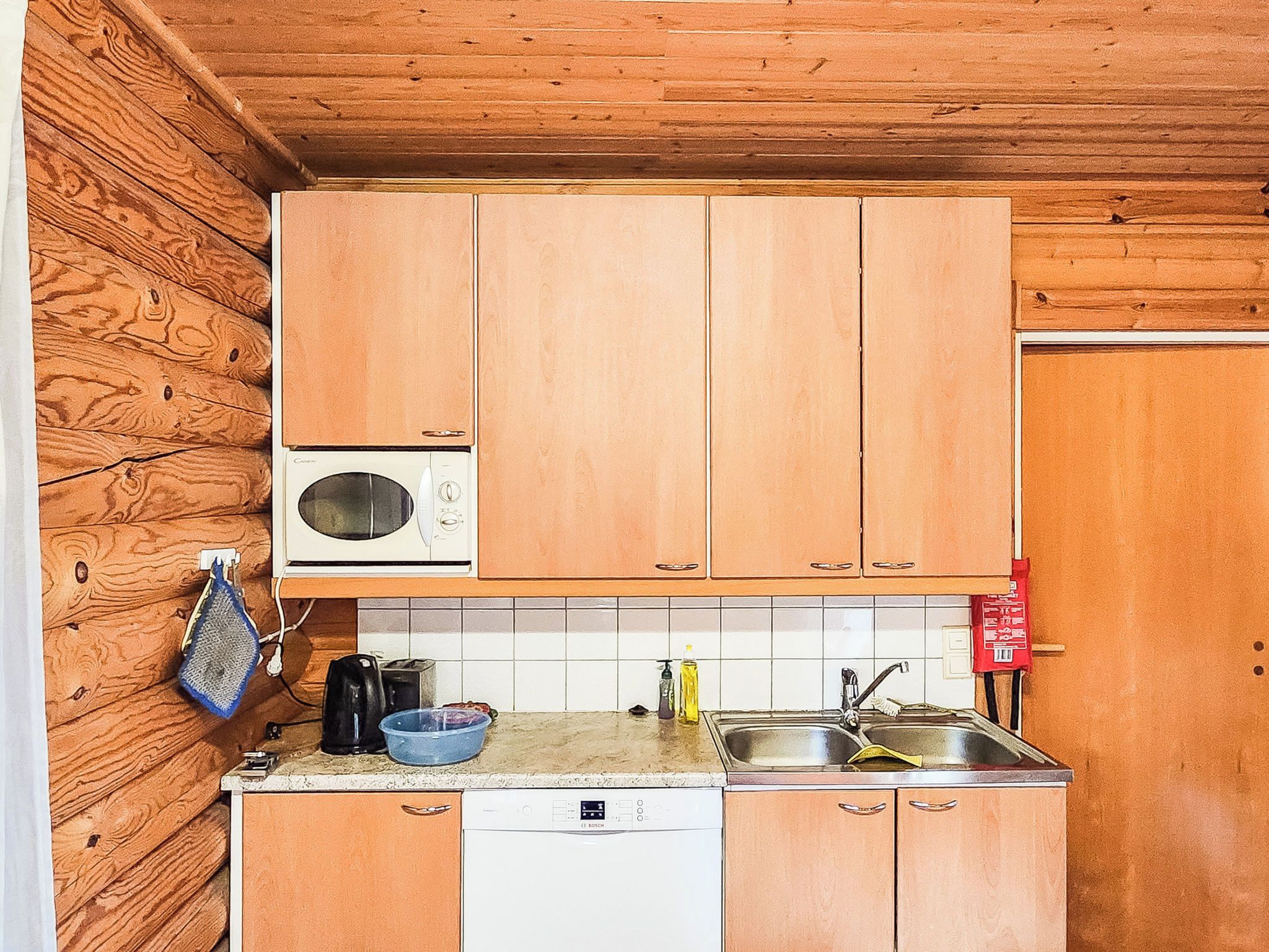 A compact kitchen with wooden cabinets, a microwave, a dishwasher, and a sink.