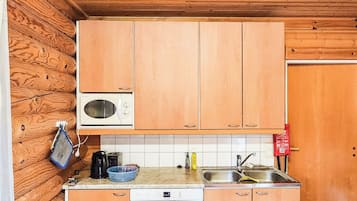 A compact kitchen with wooden cabinets, a microwave, a dishwasher, and a sink.