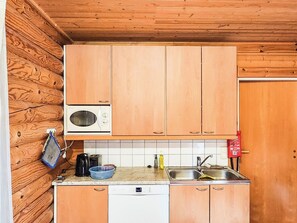 A compact kitchen with wooden cabinets, a microwave, a dishwasher, and a sink.