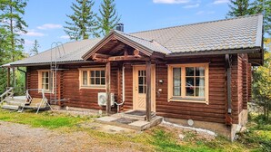Une cabane en bois dotée d’une véranda, d’un petit escalier et d’un ventilateur fixé au mur extérieur.