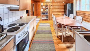Une cuisine de style rustique, avec des meubles en bois, un poêle et un coin repas comprenant une table et des chaises.