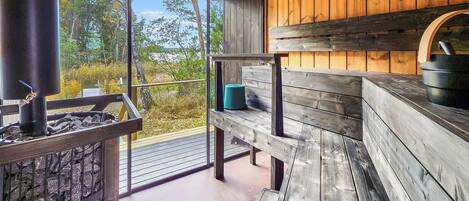 A wooden cabin with a stone fireplace, a bench, and a view of the outdoors.