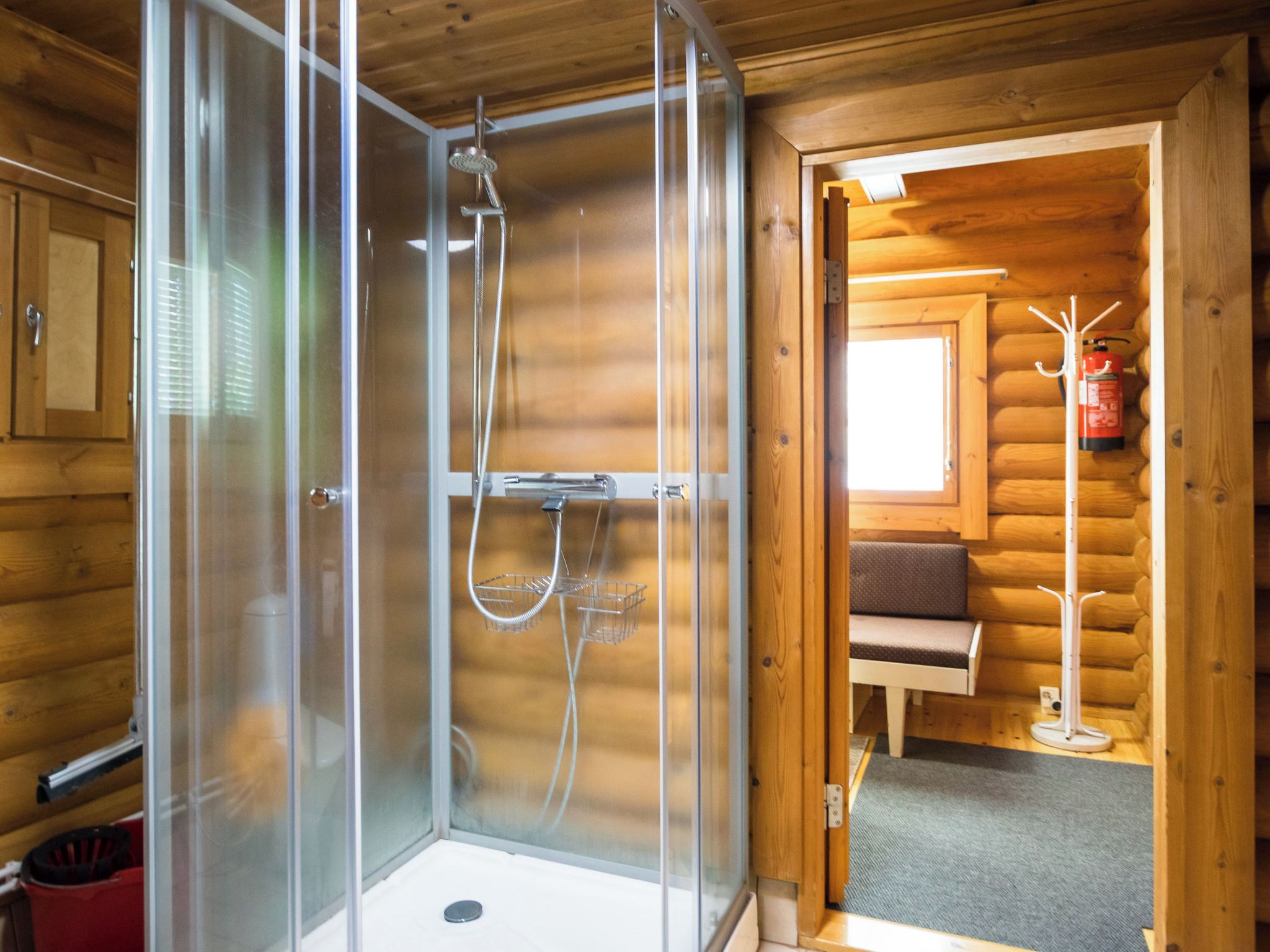 Un área de ducha con paredes de vidrio y un interior tipo cabaña de madera.