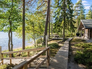 A wooden deck leading to a cabin by a lake, surrounded by trees. - Mökinniemi by Interhome (Juva)