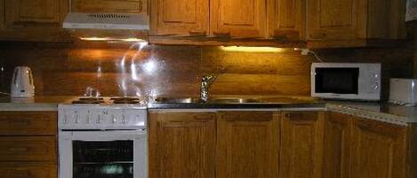 Een koelkast, een microgolfoven, kookgerei, borden en bestek