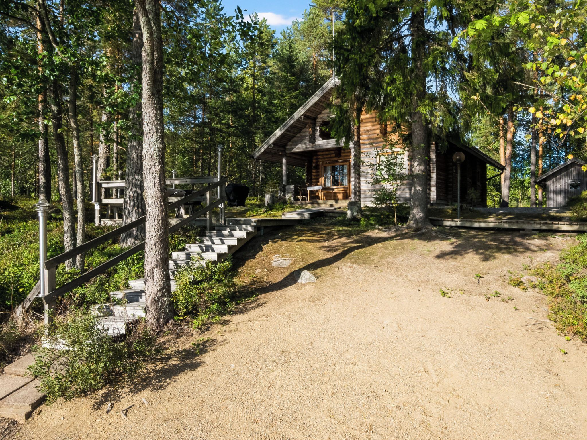 A cabin with a wooden staircase leading to a porch, surrounded by trees.