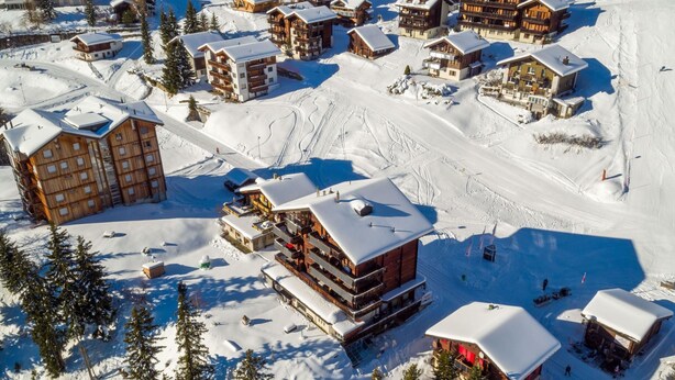 A snow-covered ski resort with multiple wooden lodges, ski trails, and a mountainous backdrop. - Bürcher Haus 1. OG Süd-West by Interhome (Riederalp)