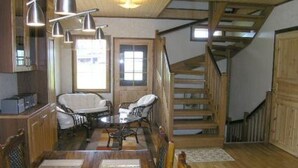 Ein Essbereich mit Holztisch und Stühlen, einer Chandelieber und einer Treppe, die in ein Obergeschoss führt.