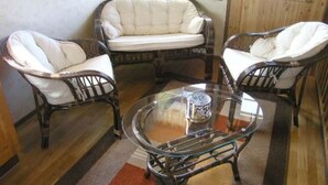 Ein Zimmer mit einem Glastisch und Korbstühlen mit weißen Kissen.
