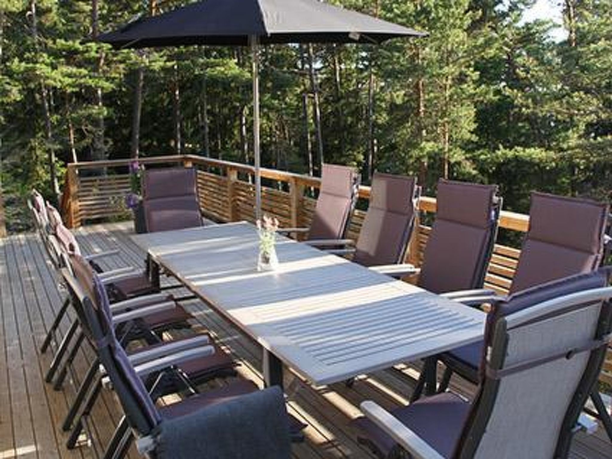 Une terrasse dotée d’une table et de chaises, entourée d’une rambarde en bois.