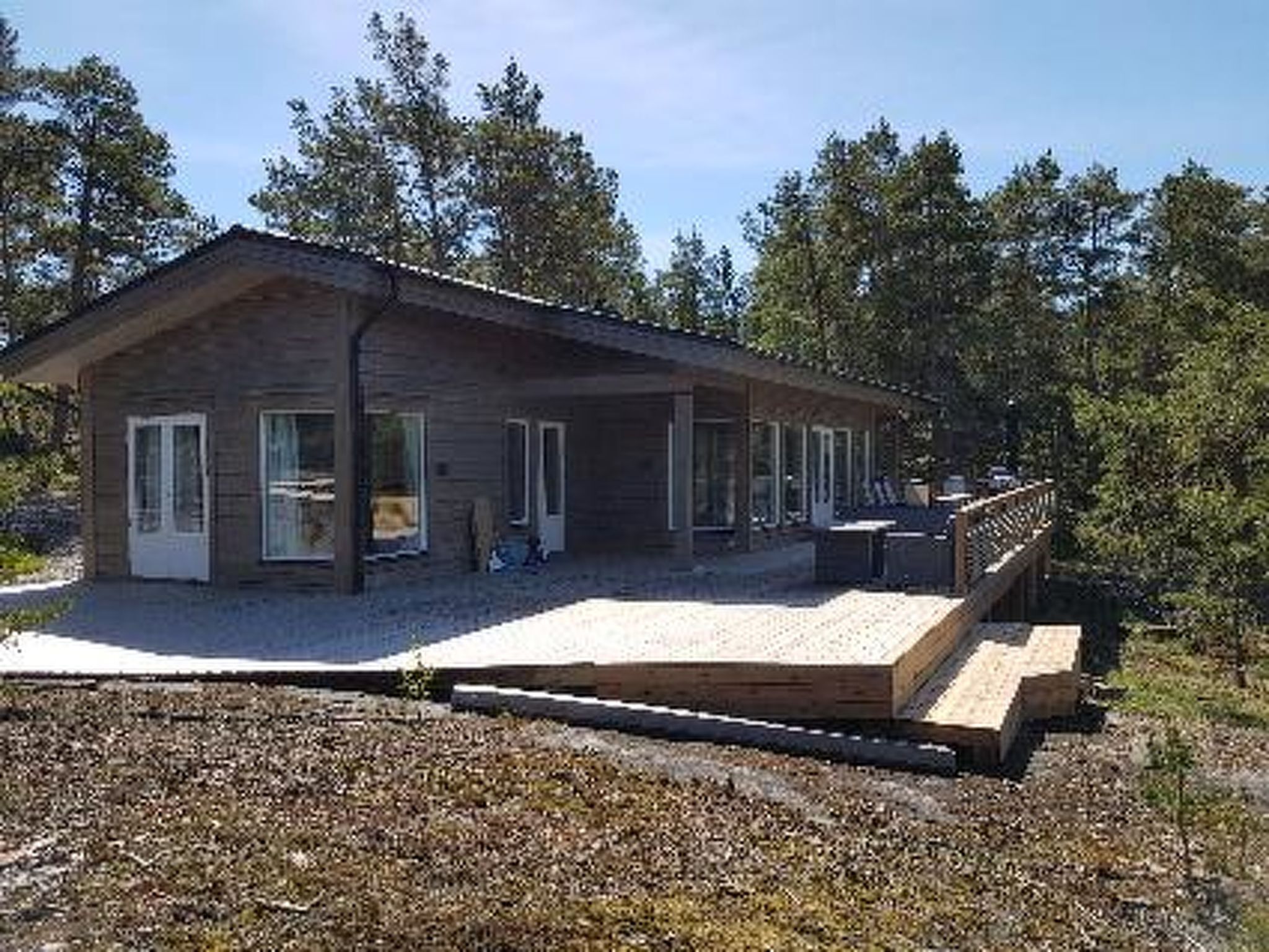 Une petite maison en bois d’un seul étage, dotée d’un porche couvert et d’une terrasse.