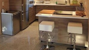 Eine moderne Küche mit Holzschränken, Edelstahlgeräten und einer zentralen Kochinsel mit Barhocker.