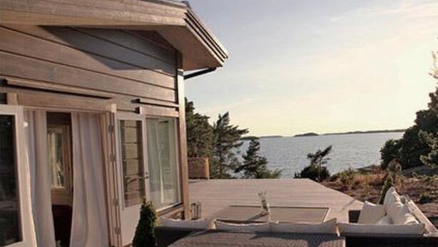 Ein modernes Haus mit einer Terrasse mit Blick auf ein Gewässer.