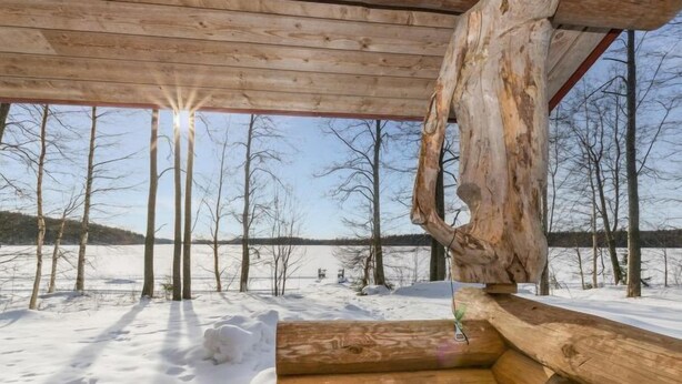 Una cabaña de troncos con un banco de madera y vistas a un paisaje nevado.